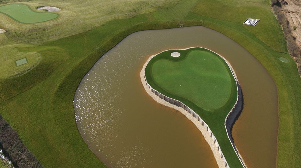 Augusta Aerial view of a vibrant green synthetic grass island in a natural pond on a golf course
